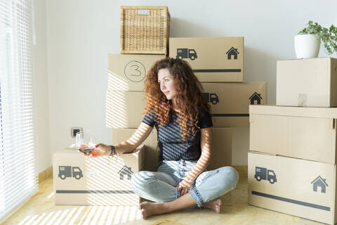 Young woman sitting in new home with glass of red wine stock photo