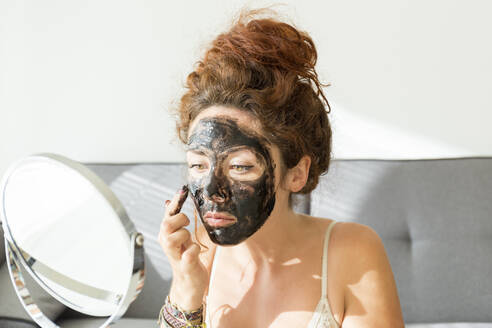 Junge Frau beim Auftragen einer Gesichtsmaske zu Hause - JPTF00234