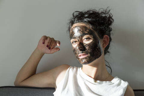 Portrait of young woman wearing facial mask at home stock photo