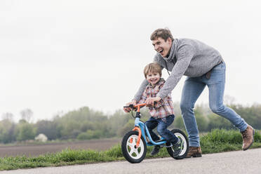 Vater bringt seinem Sohn das Fahrradfahren bei, im Freien - UUF17991