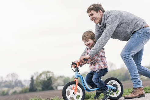 Vater bringt seinem Sohn das Fahrradfahren bei, im Freien - UUF17992