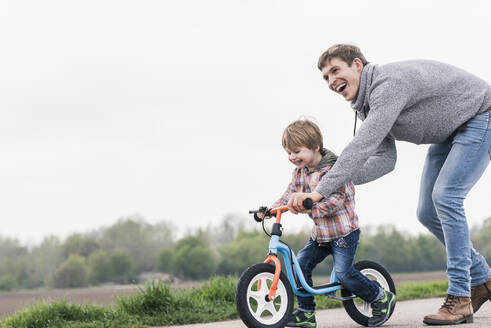 Vater bringt seinem Sohn das Fahrradfahren bei, im Freien - UUF17993