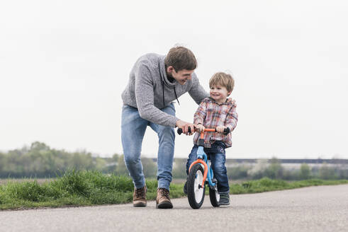 Vater bringt seinem Sohn das Fahrradfahren bei, im Freien - UUF17995