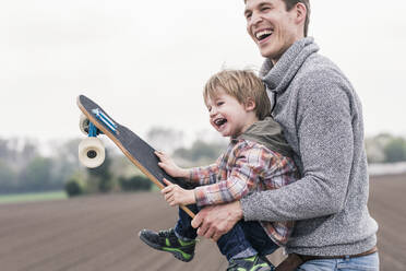 Vater und Sohn haben Spaß, spielen mit Skateboard im Freien - UUF17999