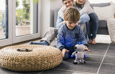 Eltern beobachten ihren Sohn, der mit einem Spielzeugroboter spielt - UUF18007