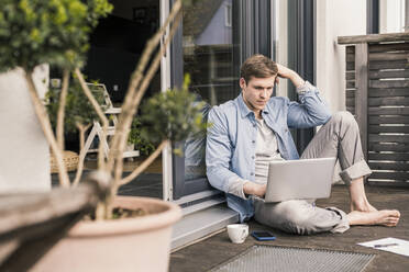 Man sitting on terrace, using laptop - UUF18037
