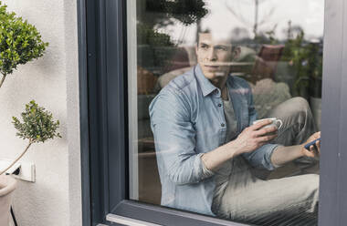 Man sitting st the window, drinking coffee - UUF18040