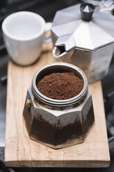 Hohe Winkelansicht von gemahlenem Kaffee mit Behälter mit Tasse und Maschine auf Holztablett in der Küche - ALBF00878