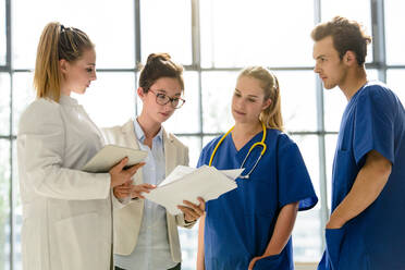 Junge Ärztinnen und Ärzte in Ausbildung sehen sich im Krankenhaus Krankenakten an - CUF51624