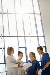 Young female and male junior doctors looking at medical records in hospital - CUF51625