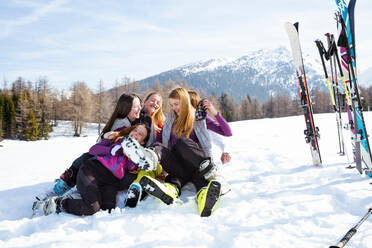 Five teenage girl skiers sitting and fooling around in snow covered landscape, Tyrol, Styria, Austria - CUF51631
