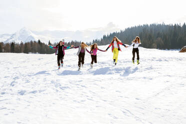 Fünf jugendliche Skifahrerinnen laufen und lachen in einer verschneiten Landschaft, Tirol, Steiermark, Österreich - CUF51648