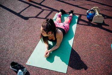 Calisthenics-Kurs in einem Fitnessstudio im Freien, junge Frau macht eine Pause auf einer Yogamatte - CUF51690