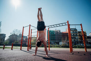 Gymnastik im Freien, junger Mann macht Handstand, Rückansicht - CUF51692