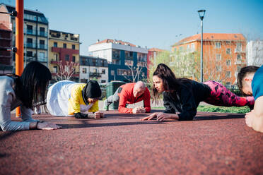 Calisthenics class in park, males and females doing push ups - CUF51700