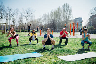 Calisthenics-Kurs in einem Fitnessstudio im Freien, Frauen und Männer üben die Yoga-Hockstellung - CUF51710