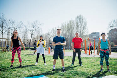 Calisthenics-Kurs in einem Fitnessstudio im Freien, Frauen und Männer üben Yoga - CUF51711