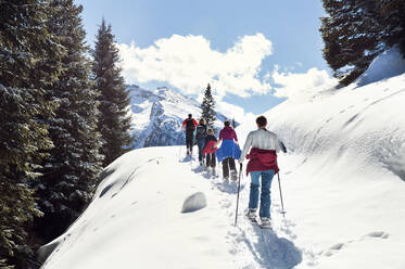 Älteres Paar und Töchter beim Schneeschuhwandern in verschneiter Berglandschaft, Rückansicht, Steiermark, Tirol, Österreich - CUF51712