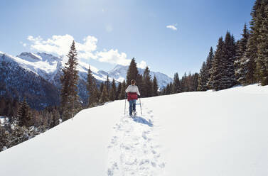 Jugendliches Mädchen beim Schneeschuhwandern in verschneiter Berglandschaft, Rückansicht, Steiermark, Tirol, Österreich - CUF51714