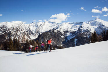 Älteres Paar und Töchter beim Schneeschuhwandern in einer verschneiten Berglandschaft, Steiermark, Tirol, Österreich - CUF51718