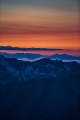 Orangefarbenes Leuchten am Horizont über einer Bergkette, Saas-Fee, Wallis, Schweiz - CUF51754