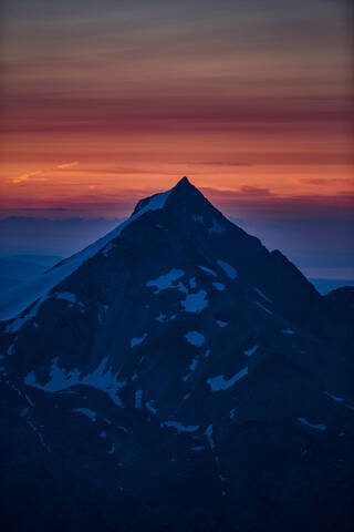 Berggipfel, orangefarbenes Glühen am Horizont im Hintergrund, Saas-Fee, Wallis, Schweiz, lizenzfreies Stockfoto