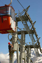 Maintenance worker climbing up cable car, Saas-Fee, Valais, Switzerland - CUF51765