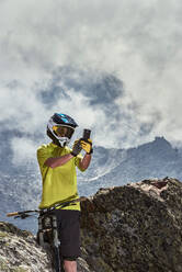 Mountain biker taking photo, Saas-Fee, Valais, Switzerland - CUF51772