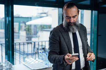 Businessman using smartphone in office - CUF51795