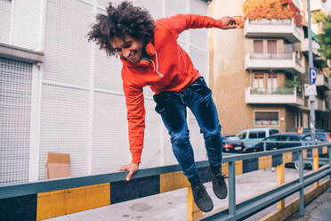 Junger Mann springt über Trennwand auf Bürgersteig, Mailand, Lombardei, Italien - CUF51838