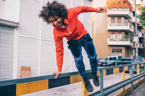 Junger Mann springt über Trennwand auf Bürgersteig, Mailand, Lombardei, Italien - CUF51838