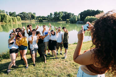 Woman taking photograph of friends by lake - CUF51859