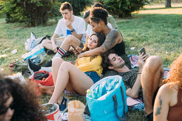 Eine Gruppe von Freunden entspannt sich bei einem Picknick im Park - CUF51895