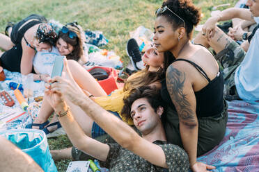 Group of friends relaxing, taking selfie at picnic in park - CUF51896