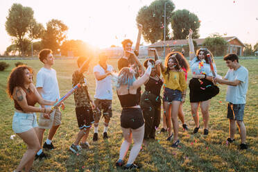 Group of friends playing with confetti in park - CUF51904