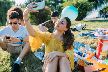 Group of friends relaxing, taking selfie at picnic in park - CUF51912