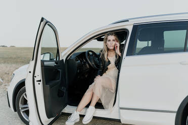 Blond woman using smartphone, sitting in white car - ERRF01520