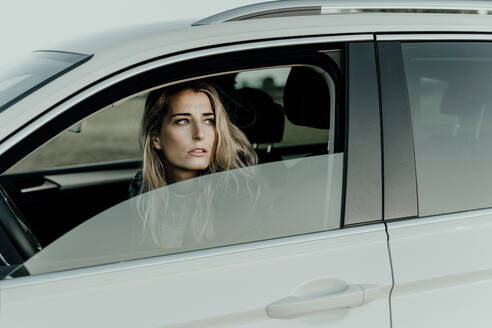 Blonde Frau in weißem Auto schaut aus dem Fenster - ERRF01528