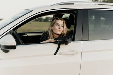 Blonde Frau in weißem Auto schaut aus dem Fenster - ERRF01529