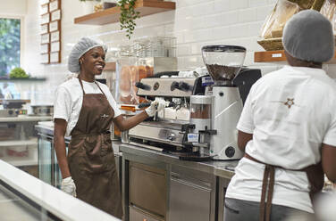 Junge Frau arbeitet in einer Eisdiele und bedient eine Kaffeemaschine - VEGF00380