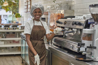 Junge Frau arbeitet in einer Eisdiele und bedient eine Kaffeemaschine - VEGF00383