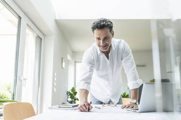 Architekt bei der Arbeit an einem Entwurf in einem hellen Büro, mit Laptop - UUF18046