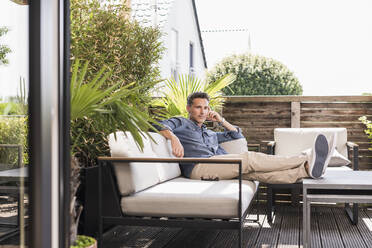 Confident man relaxing on the terrace - UUF18123