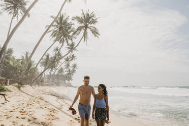 Glückliches Paar, das gemeinsam am Strand spazieren geht, während es seinen Urlaub in Sri Lanka genießt - LHPF00720