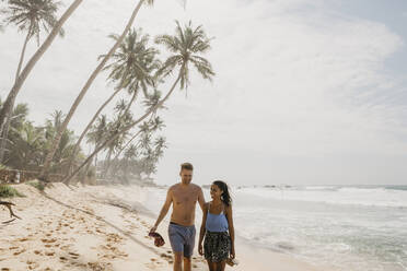 Happy couple walking together at beach while enjoying vacations in Sri Lanka - LHPF00720