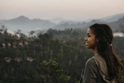 Lächelnder Forscher mit Blick auf einen Berg bei Sonnenuntergang, Sri Lanka, lizenzfreies Stockfoto