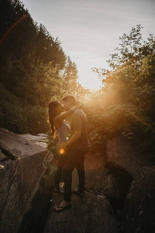 Full length of couple kissing against plants in forest during sunny day, Sri Lanka stock photo