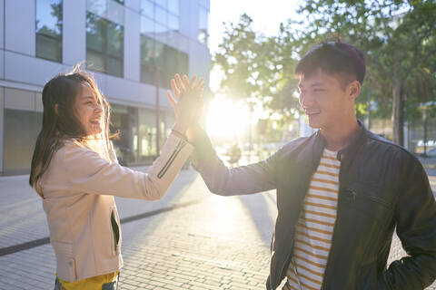 Lächelndes Paar, das sich bei Sonnenuntergang die Hand gibt, lizenzfreies Stockfoto