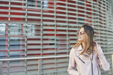 Porträt einer Frau mit rosa Lederjacke und Sonnenbrille, Barcelona, Spanien - DVGF00022