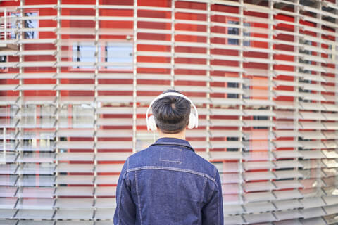 Rückenansicht eines jungen Mannes, der mit Kopfhörern Musik hört, Barcelona, Spanien, lizenzfreies Stockfoto